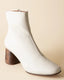 White ankle boot with wooden heel on a beige background