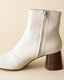 White ankle boot with wooden heel on a beige background