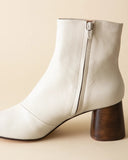 White ankle boot with wooden heel on a beige background